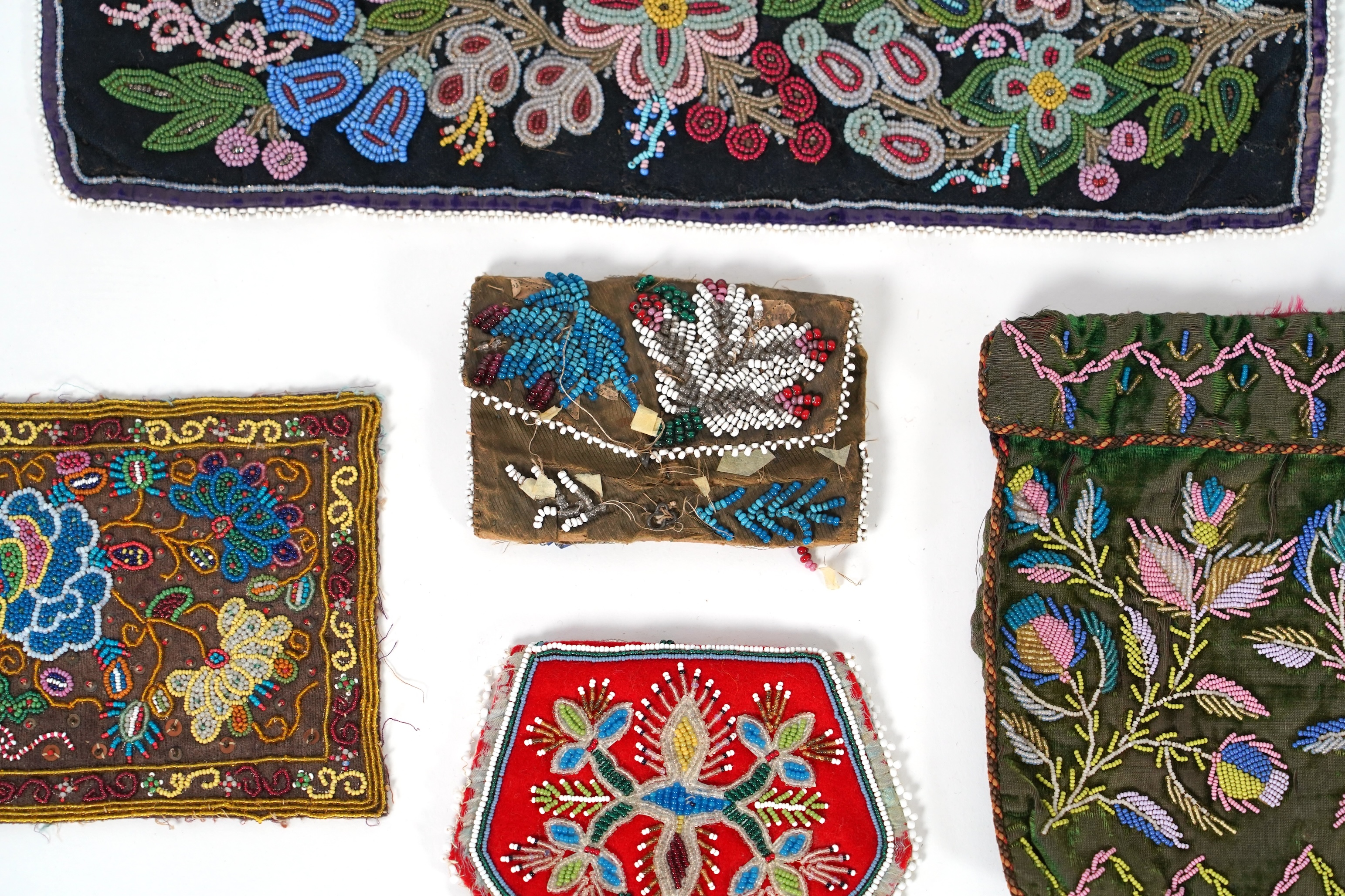A 19th century black felt multi coloured beadwork panel, possibly North American Indian and a similar purse, a Regency fine bead worked bible bag, a similar worked belt and small panel, a red bead work purse and a small